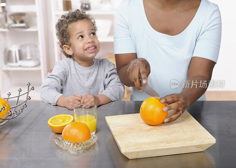 蹒跚学步的孩子/小男孩因妈妈做橙汁而兴奋